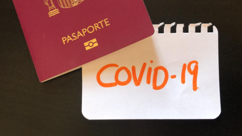 Image of a passport and a pice of paper COVID-19 writen