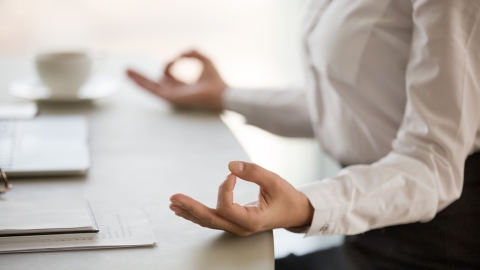 Una dona amb les mans en posició meditativa davant de l'ordinador