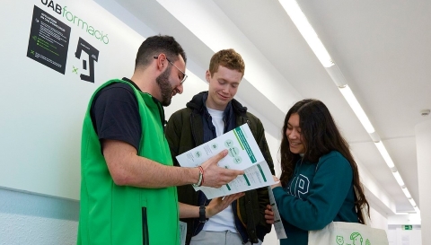 Dos futurs estudiants consulten un díptic amb personal de l'escola