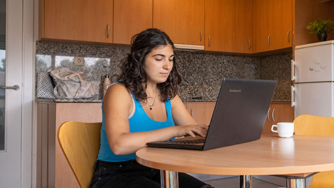 Estudiant a la vila consultant el seu portàtil