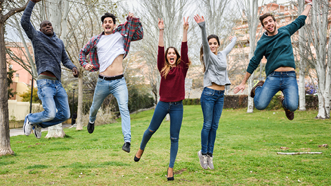 Estudiants saltant en un prat verd