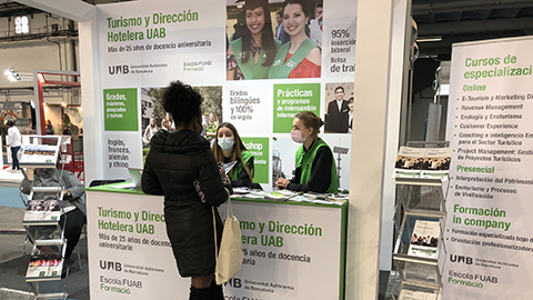 Estudiants del centre atenent a una visitant de l'estand al Saló B-Travel 2022