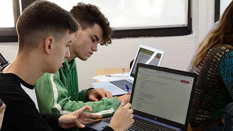 Dos nois a classe amb un ordinador