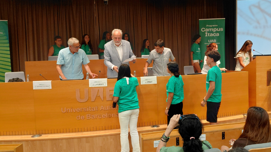 El rector lliurant diplomes a alumnes del Campus Itaca a la sala d'actes.