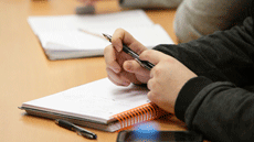 Detall d'un estudiant prenent notes