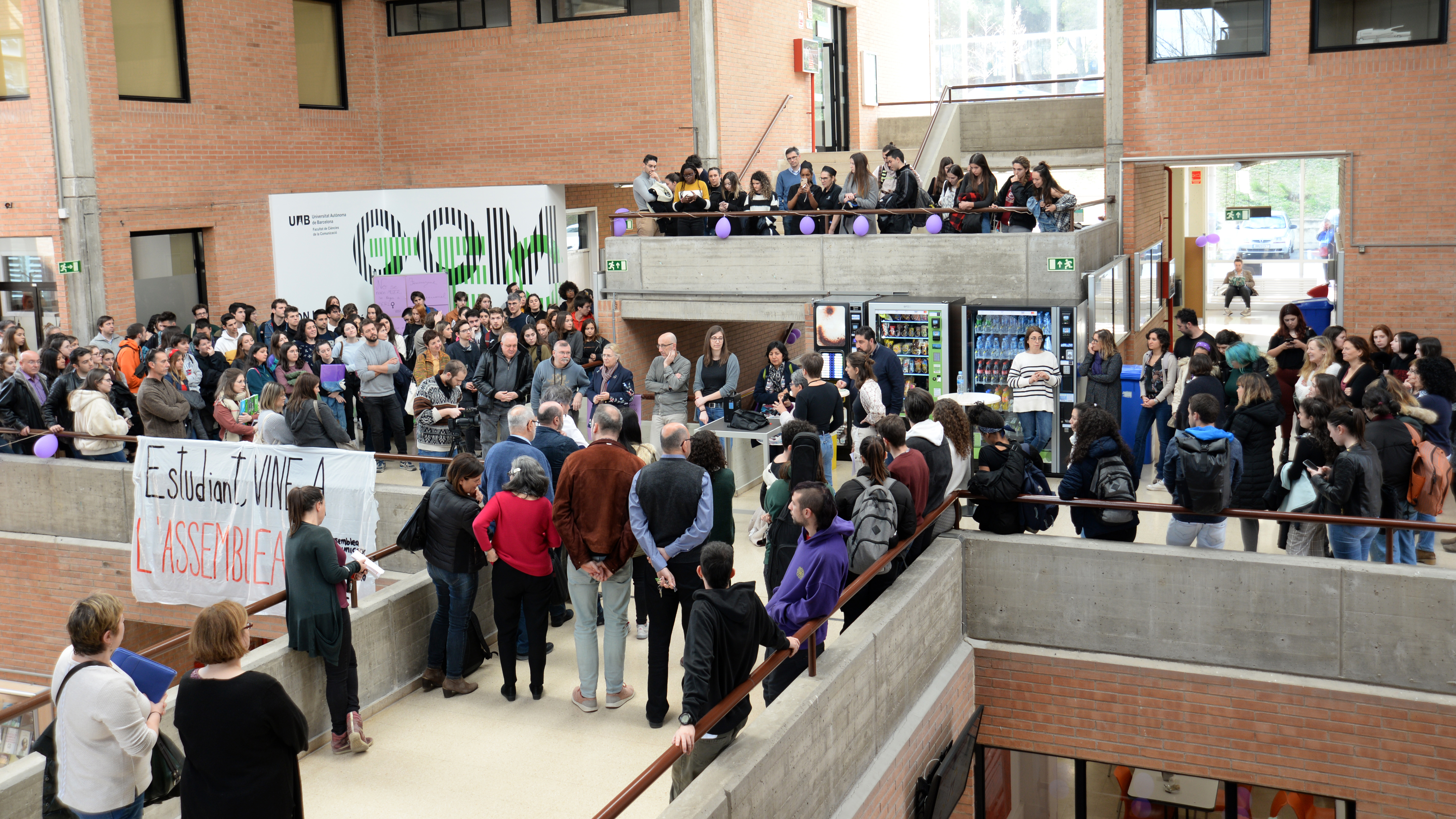 Pla general del hall de la Facultat ple de gent pels actes del Dia de la Dona