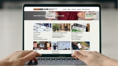 Portàtil amb una web a pantalla i les mans d'una persona que teclegen