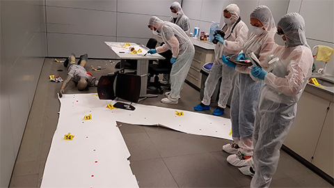 Estudiants amb equipament protector fent fotos a una escena d'un fet criminal