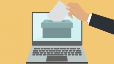 Il·lustració d'una mà introduint un vot a una urna dins un ordinador