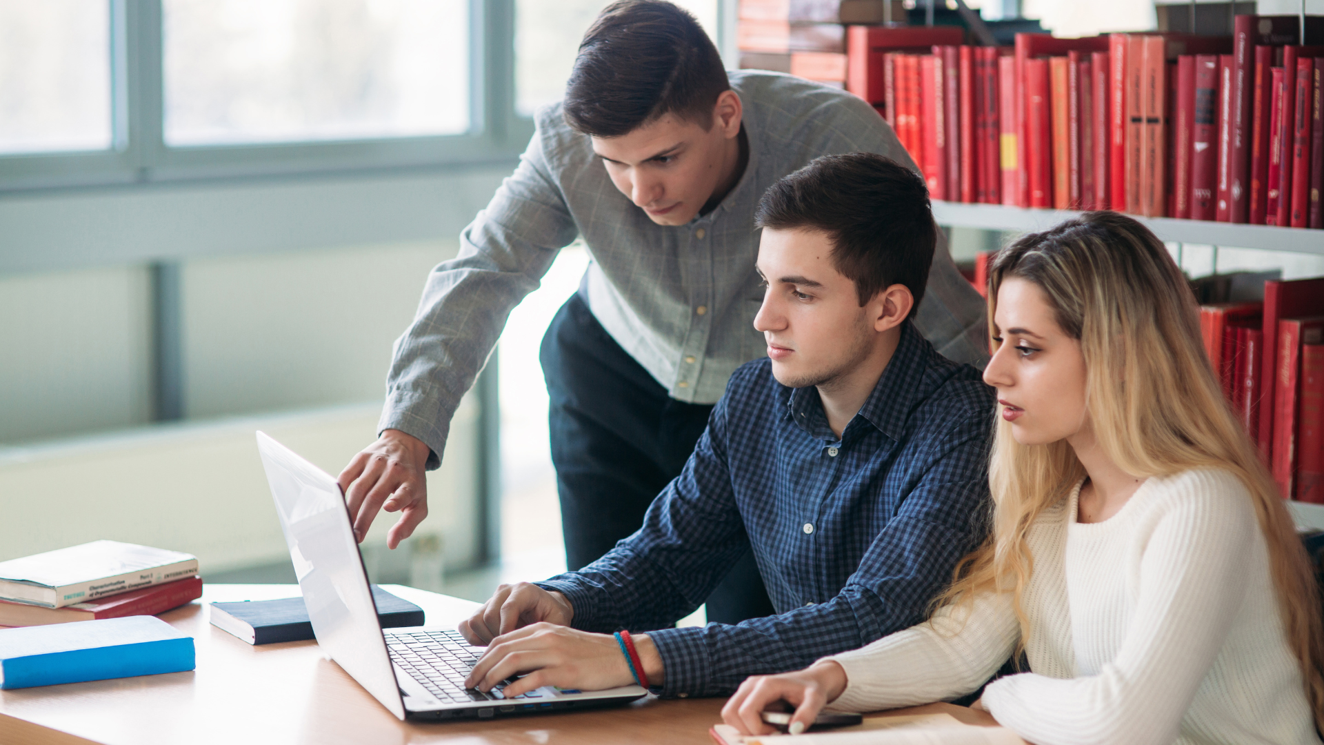 3 estudiantes consultando información al ordenador