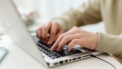 Mans escrivint a un portàtil