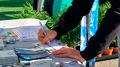 Una persona omple un formulari sobre una taula amb pamflets informatius 