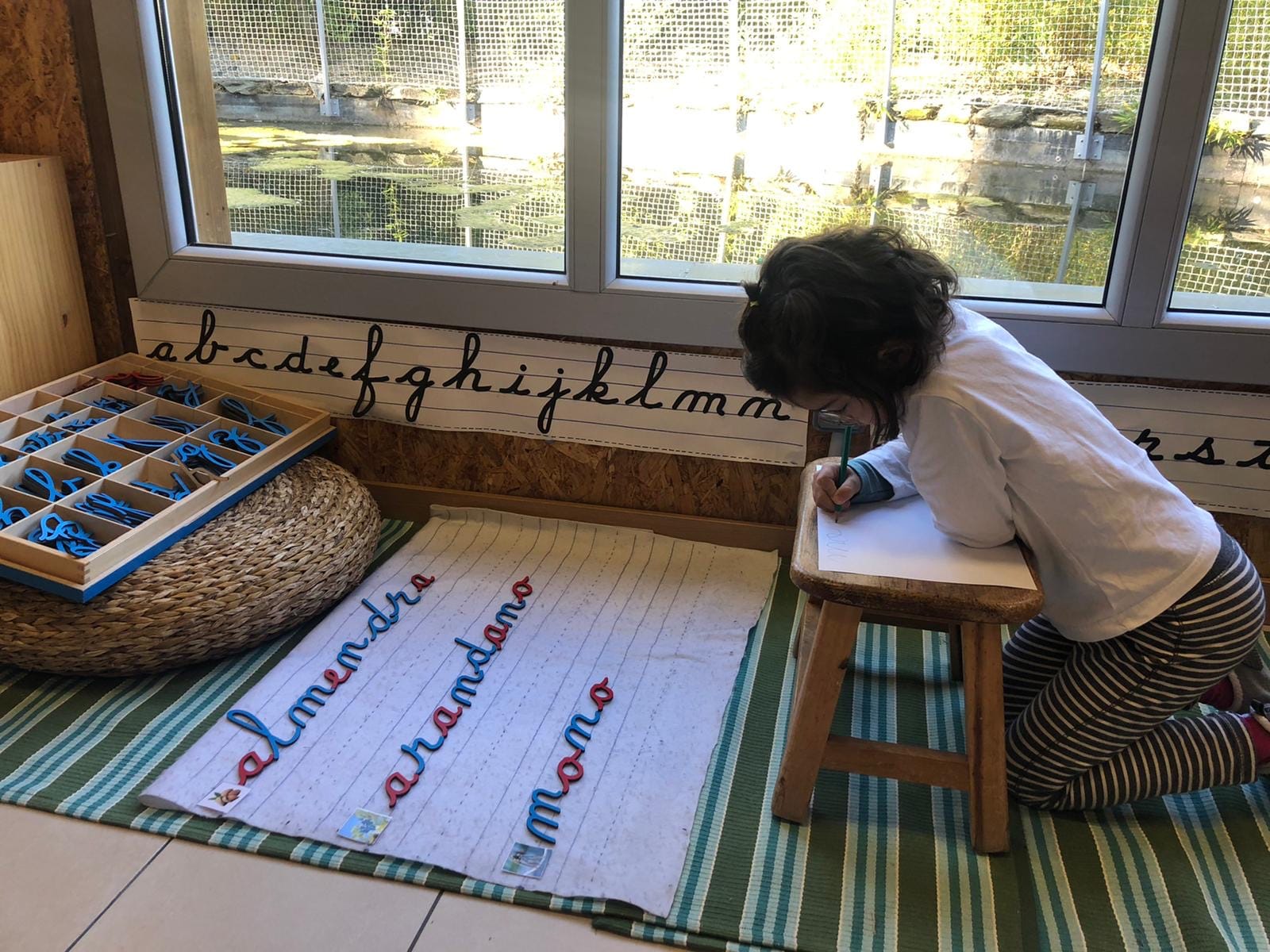 Nena aprenent a escriure en una classe.