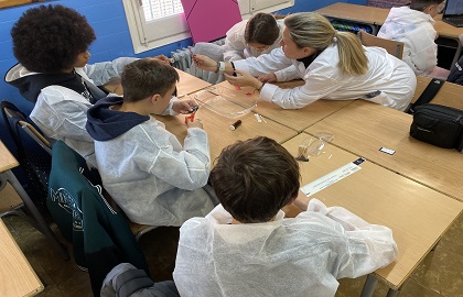 Un grup d'alumnes elaborant un experiment amb l'ajuda d'una professora