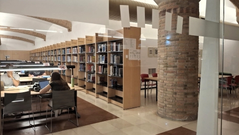 Perspectiva de la biblioteca amb estanteries amb llibres i estudiants asseguts a les taules