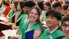 Graduats de Turisme i Direcció Hotelera amb bandes verdes somriuen a l'acte de graduació