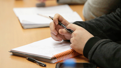 Detalle de un estudiante tomando notas