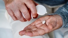 Unes mans de persona gran agafen una píndola d'un pot