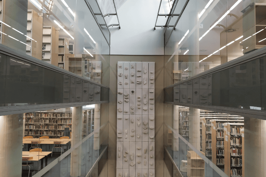 Interior de la biblioteca de comunicació amb prestatgeries amb llibres i una pared al fons