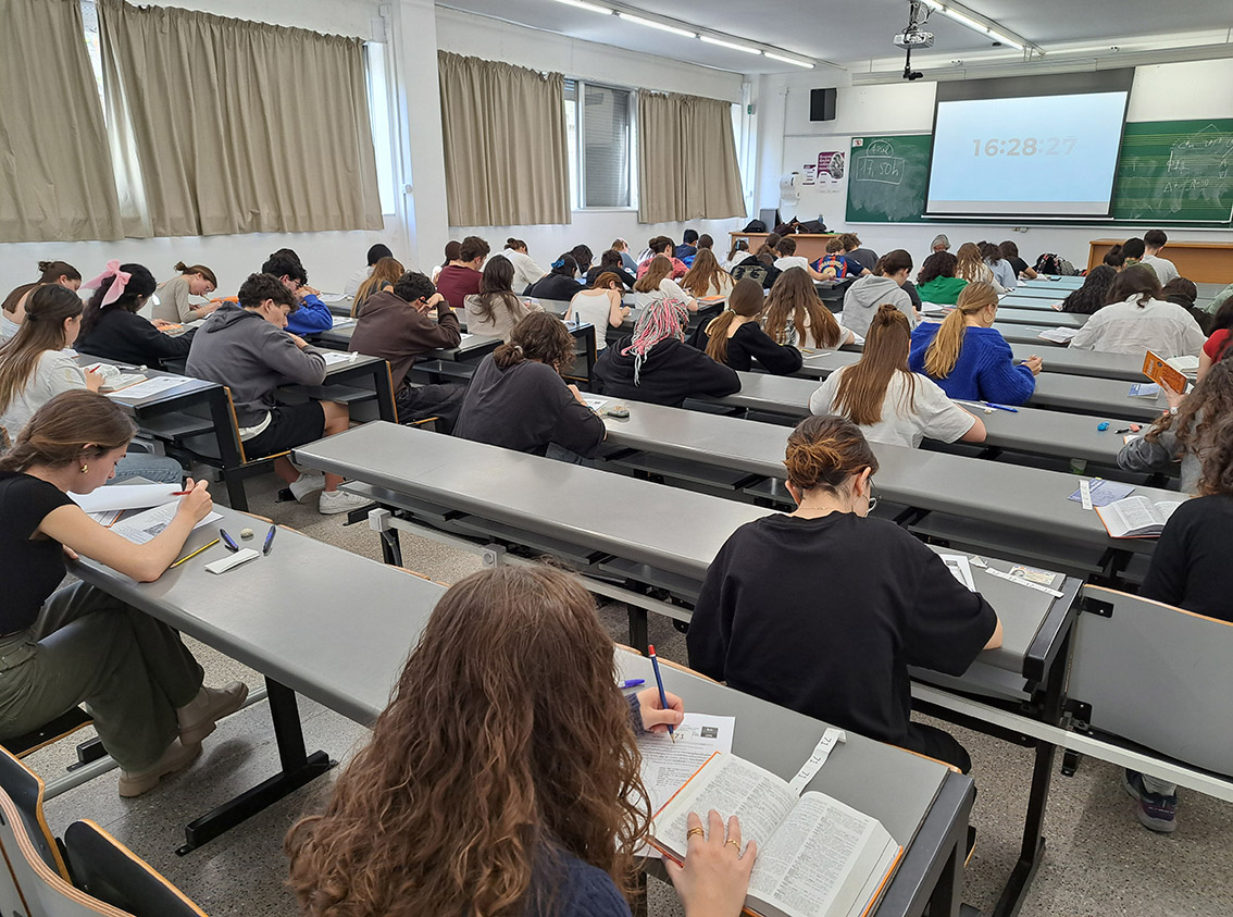  Estudiants efectuant proves escrites a una aula. Al fons es veu la projecció del temps restant per a la prova.