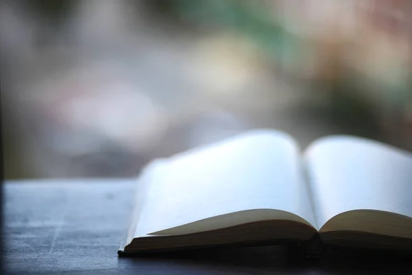  Llibre en blanc obert sobre una taula de fusta.