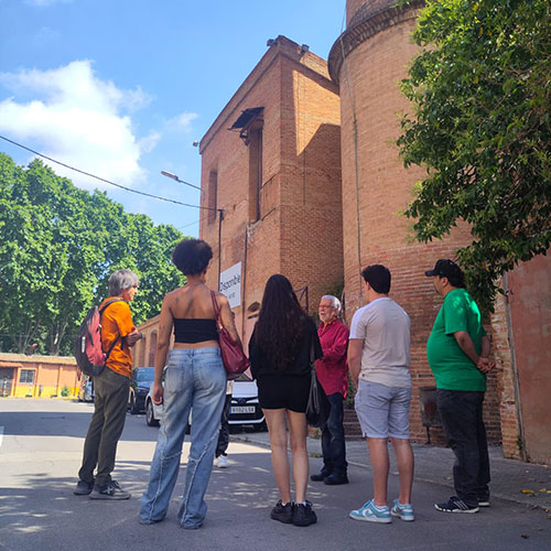 Amplia la imatge Grups d'estudiants escoltant una explicació davant d'un edifici de maó vermell