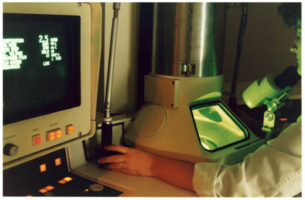 Imatge antiga on s'observa una tècnica manipulant el microscopi.