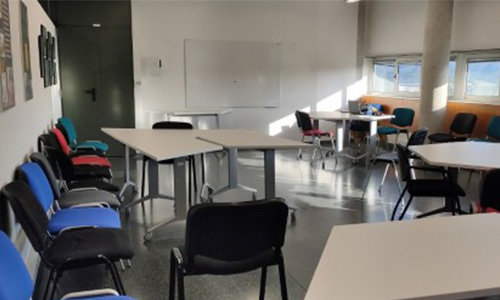 A room full of tables and chairs and a Vileda whiteboard.