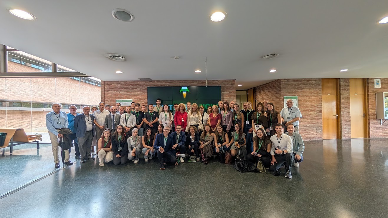 Foto de grupo de los participantes, mentores y autoridades del Ignition Day frente al videowall de la Escola d’Enginyeria