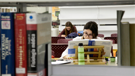 Estudiante en una mesa rodeada de libros