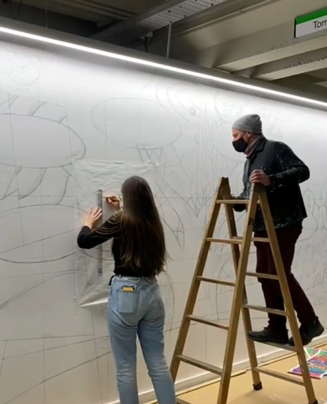 L'artista i una de les estudiants que va col·laborar, en l'etapa inicial de l'elaboració del mural.
