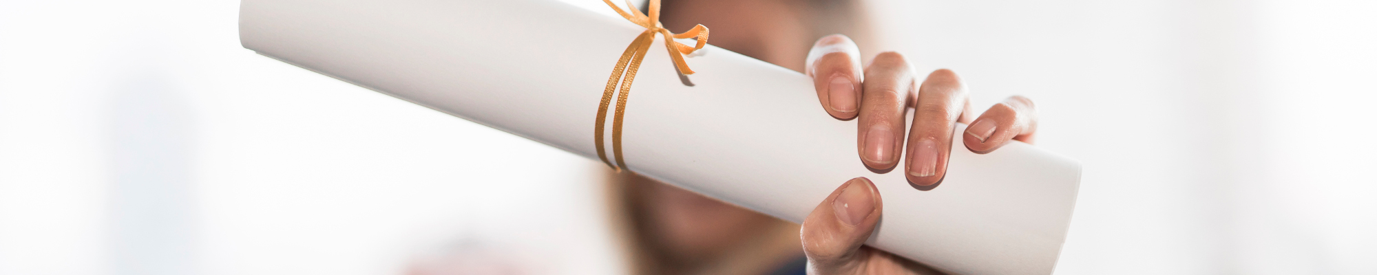 Image of someone holding a diploma with a tie