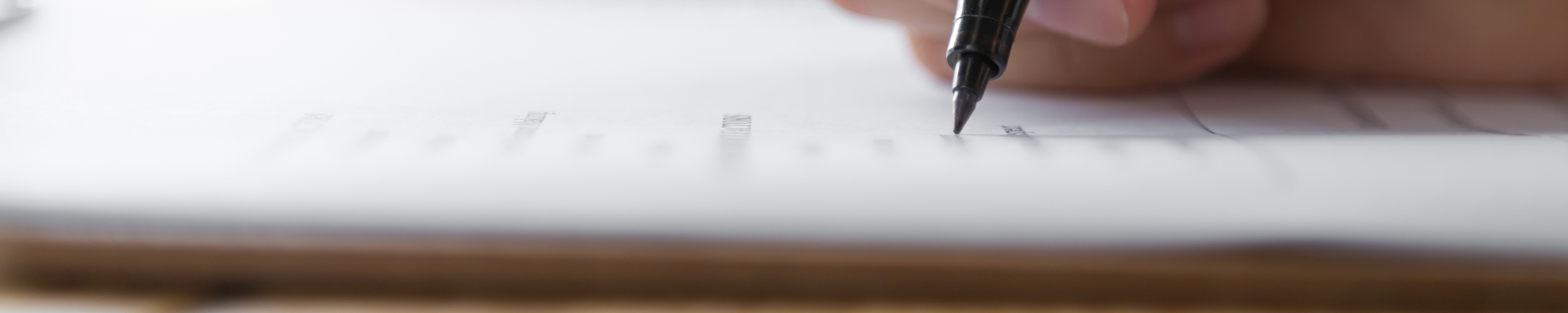 Image of a person writing on a blank piece of paper with a pen